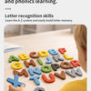 A child's hand is shown interacting with wooden letter cards spelling out the alphabet on a light wooden table.