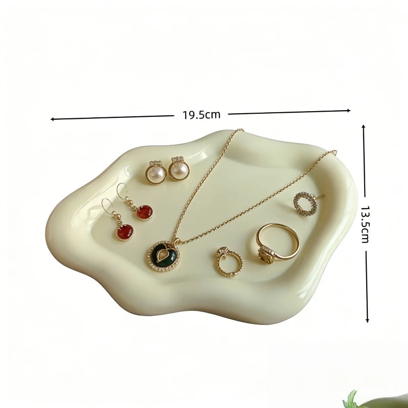 A white cloud-shaped jewelry tray displaying gold necklaces and earrings.