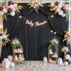 Dunkler Stoffhintergrund für eine Babyparty mit rosa und weißen Ballons, Blumenarrangements und goldenen Ständern.
