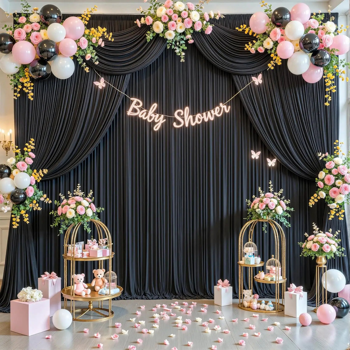 Dunkler Stoffhintergrund für eine Babyparty mit rosa und weißen Ballons, Blumenarrangements und goldenen Ständern.