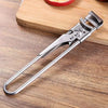 A silver adjustable stainless steel jar and bottle opener resting on a wooden cutting board.