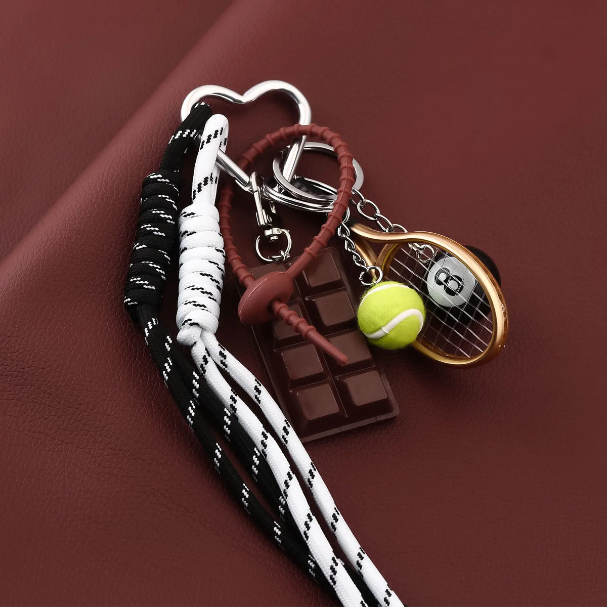A metal keychain featuring an 8-ball and a chocolate bar charm on a dark brown background.