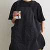 A person wearing a black waterproof work apron while holding a glass.