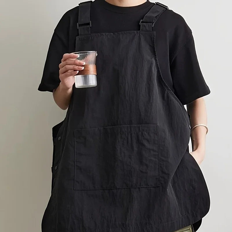 A person wearing a black waterproof work apron while holding a glass.