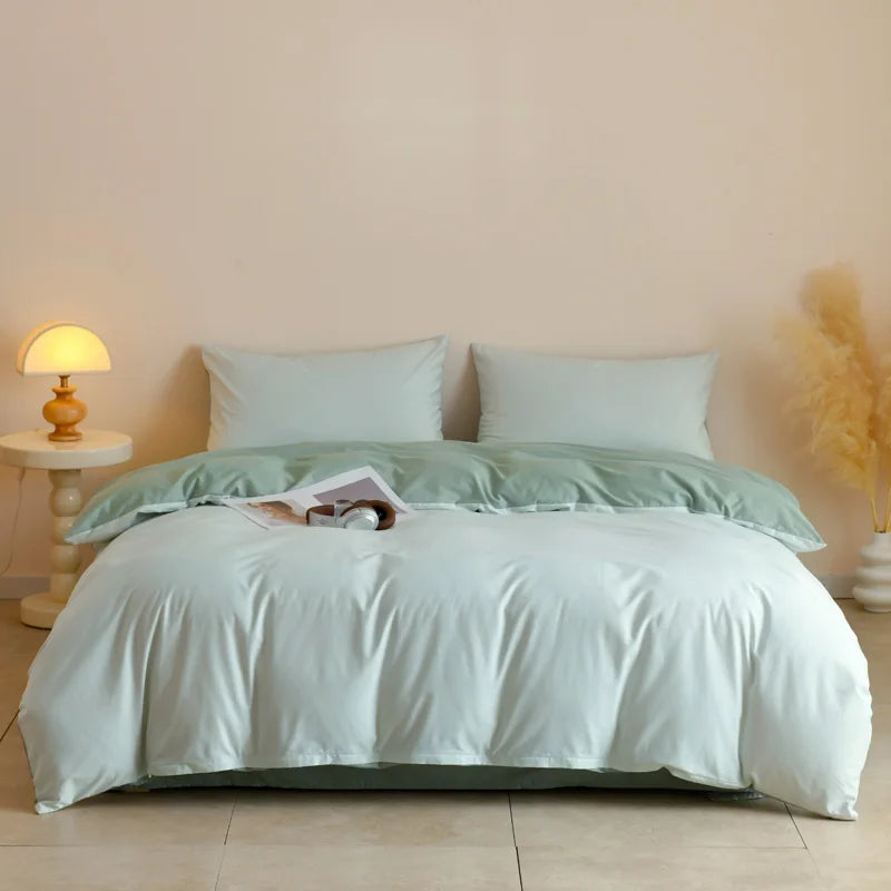 A white quilted duvet cover set with matching pillowcases on a bed, next to a bedside lamp.