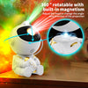 A white astronaut night light projector with built-in magnetism, showing a bright green and red light beam.