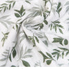 Close-up of white muslin fabric with green leaf print showing yarn density.