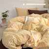 A yellow and beige striped duvet cover set displayed on a bed with brown accents.