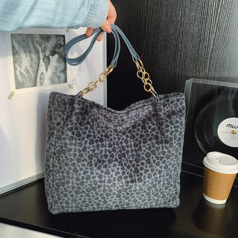 Sac en toile de léopard gris foncé avec quincaillerie dorée sur fond noir.