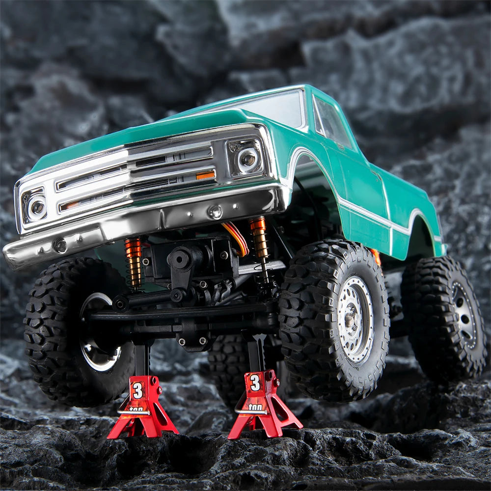 A teal RC crawler vehicle with a chrome grille is shown with a red mini jack stand and tool set.