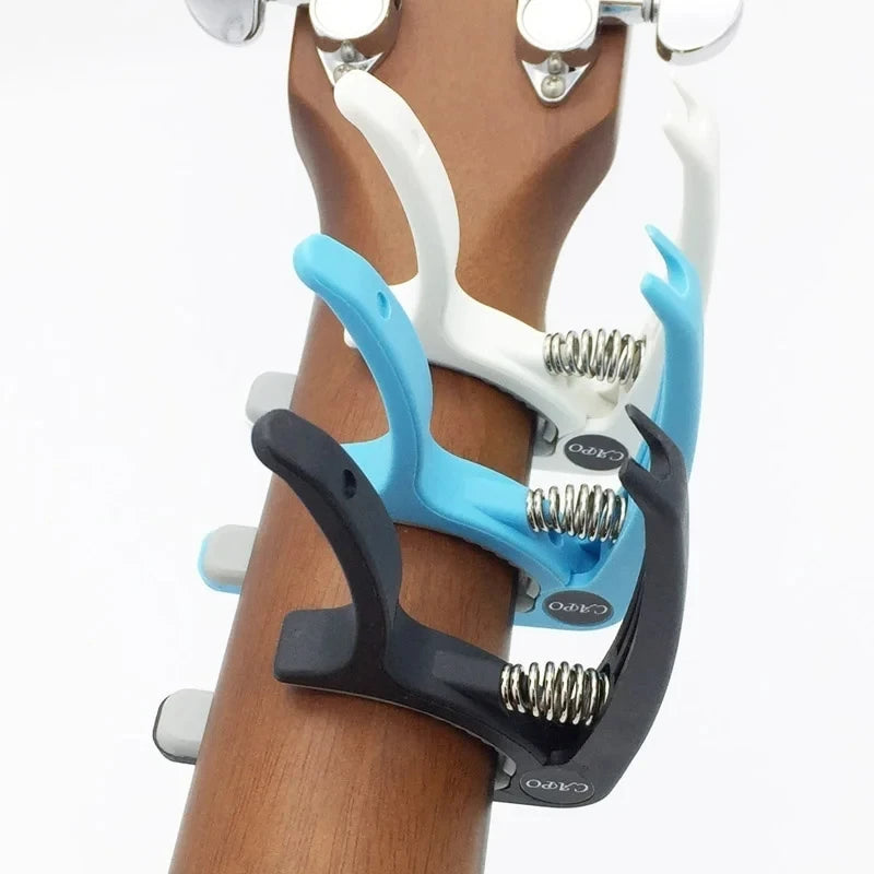Adjustable guitar capo with built-in bridge pin puller shown on a wooden neck.