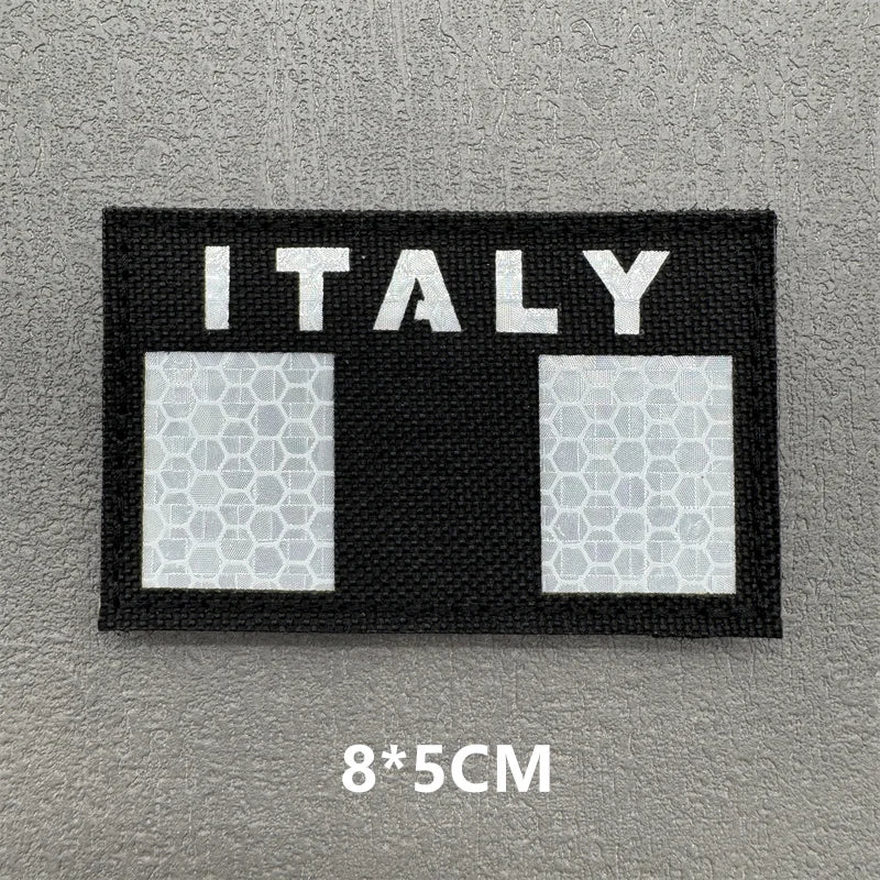 A black rectangular patch with the word ITALY in white text and two square sections featuring a geometric pattern.