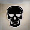A black skull design embroidered on a white felt rug mounted on a light-colored wall.