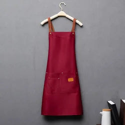 A maroon waterproof adjustable kitchen apron hanging on a wooden hanger against a gray background.