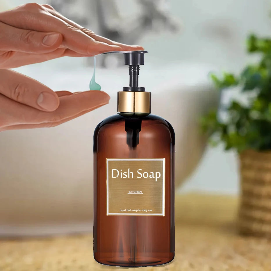 A hand is dispensing liquid dish soap from a gold pump dispenser bottle into the air.