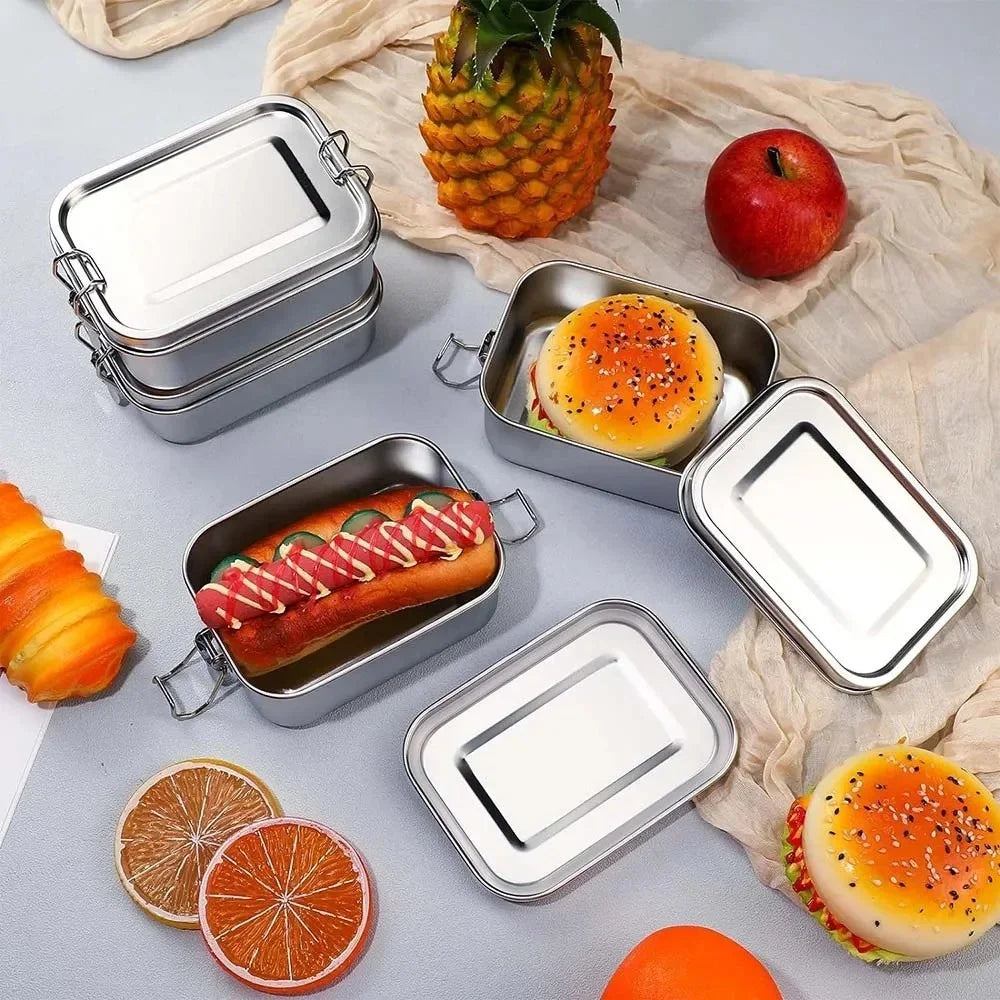 Boîte à lunch en acier inoxydable avec couvercles à verrouillage, remplie de fruits et d'un hamburger.