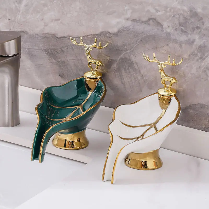 A leaf-shaped ceramic soap dish with a drain rack featuring green and white glaze and gold accents.