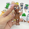 A hand holds a brown, humanoid-shaped mystery keychain blind box among several colorful plastic figures.