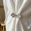 Silver rhinestone bowknot clothing clips securing a white fabric garment