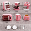 A set of pink and white fashion doll accessories including a hand mixer, a mini toaster, a mug, and cutlery.