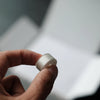 A hand holds a silver Class 15 prewound bobbin for home embroidery machines.