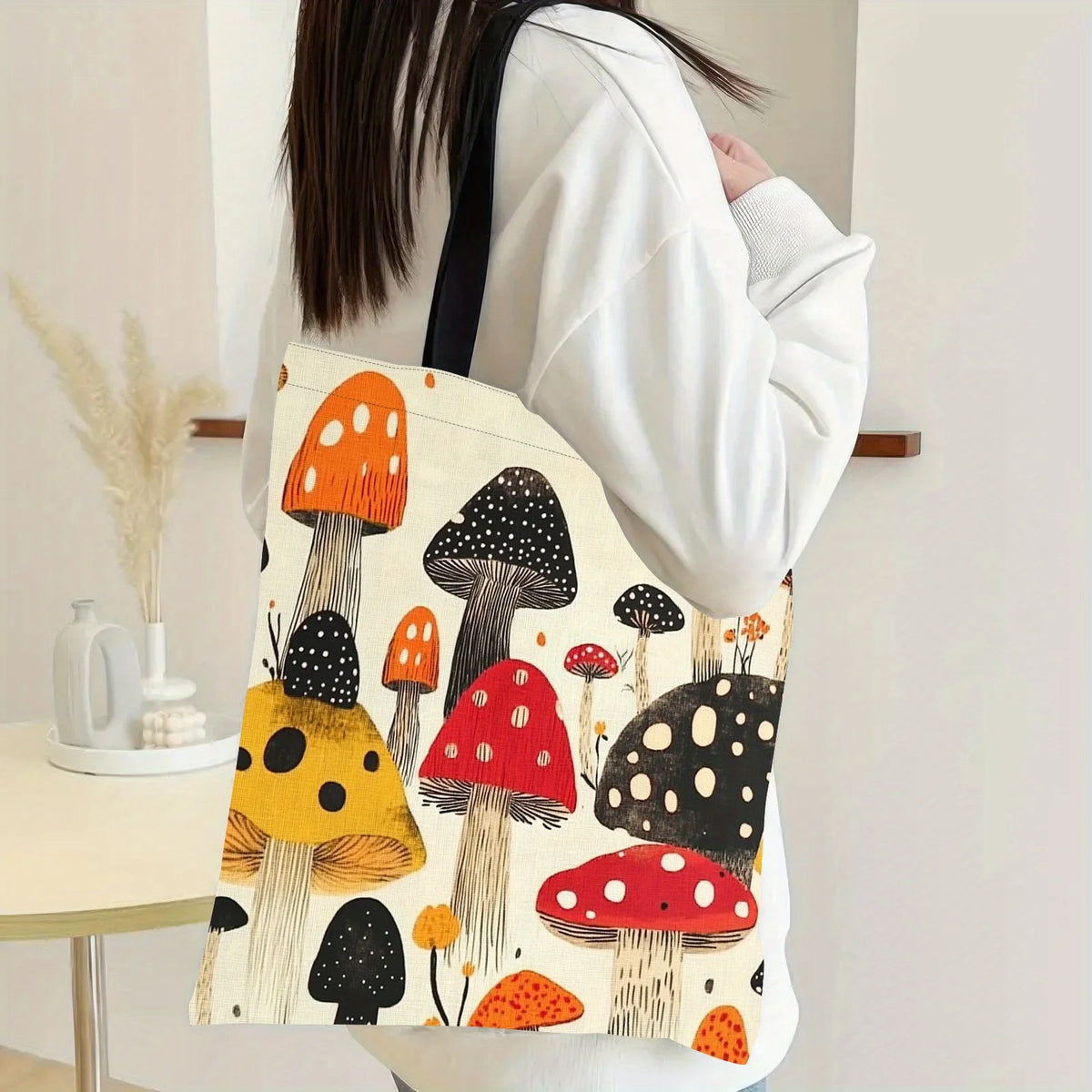 A tote bag featuring a colorful print of various mushrooms on a white background, carried by a person.