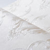 Close-up of an embossed damask wallpaper roll featuring a delicate floral design in white.