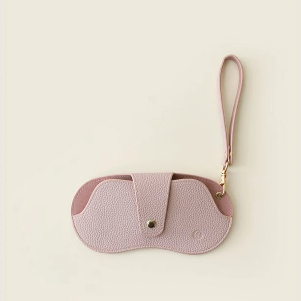 A pink PU leather glasses case with a retro lychee pattern and a thin strap.
