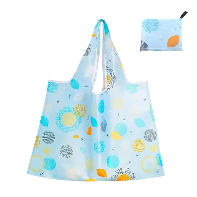 Light blue reusable shopping tote bag featuring a pattern of colorful citrus fruits and floral elements.