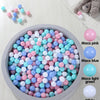 A collection of colorful, crush-proof ball pit balls in pink, blue, green, and white are displayed in a gray bowl.