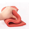 A hand is bending a red silicone heat-resistant craft mat into a curved shape.