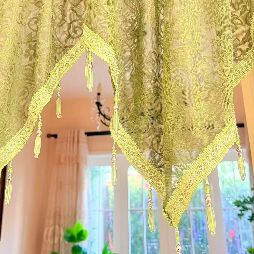 A sheer lime green lace curtain valance with gold trim hangs over a window.