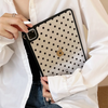 A hand holds a black polka dot protective case for an iPad, which is placed inside a white shirt.