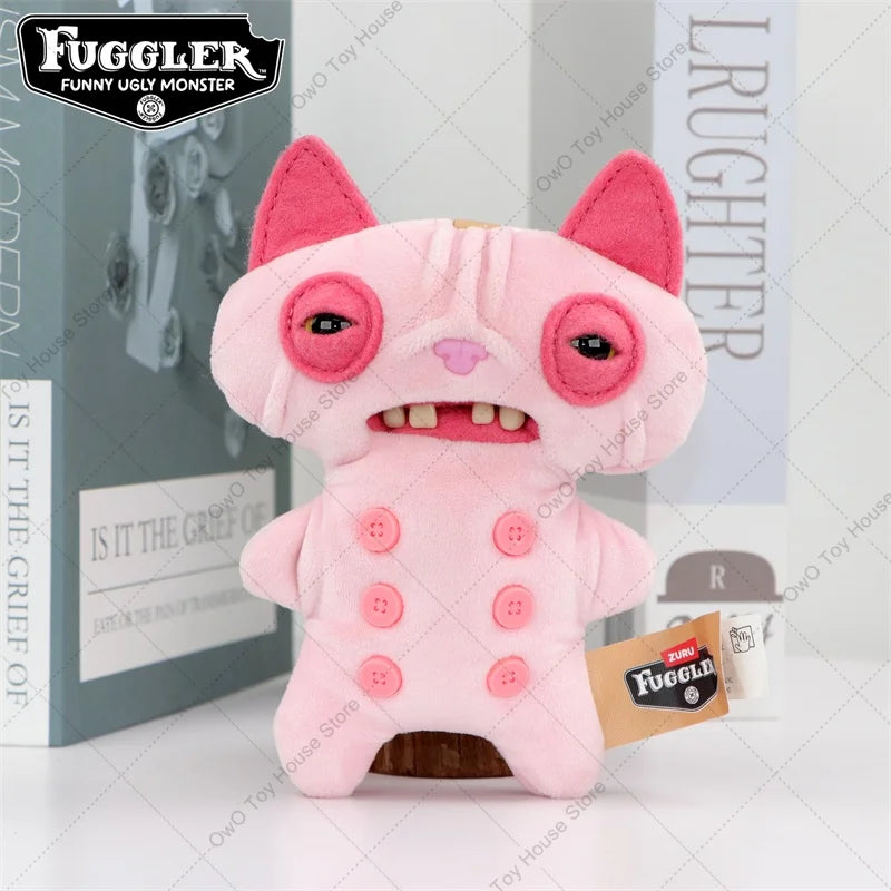 A pink Fuggler plush toy with large eyes and pink ears is displayed in front of its packaging.