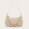 A beige straw beach shoulder bag with gold hardware and ocean shell charms