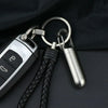 A stainless steel waterproof pill capsule attached to a keychain with a black leather cord.