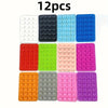 A set of 12 reusable silicone suction phone mounts in various colors including white, black, light blue, and pink.