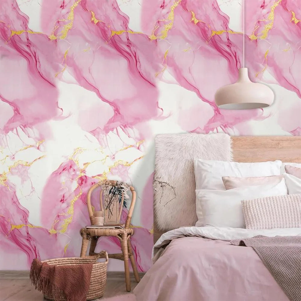 Pink and gold marble pattern wallpaper on a wall above a bed with white linens.