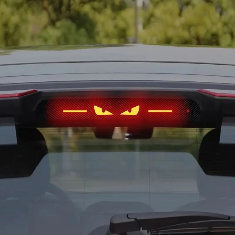 Close-up of a car's taillight featuring an aftermarket devil eye glow brake light sticker.