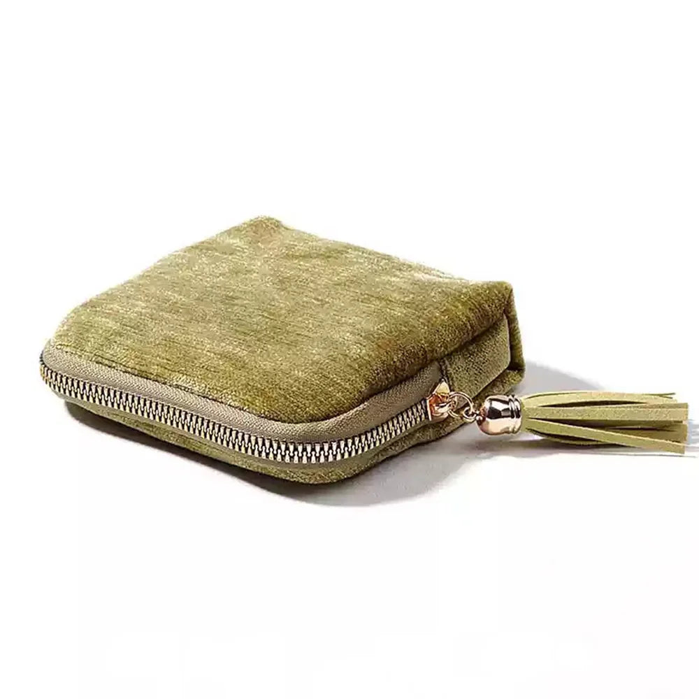 A olive green velvet jewelry organizer bag with a gold-toned tassel zipper.
