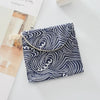 A navy blue fabric pouch with white swirling patterns and a light beige clasp closure.