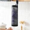 A black mesh bag dispenser hanging on a kitchen shelf, with a hand holding the bottom of the bag.
