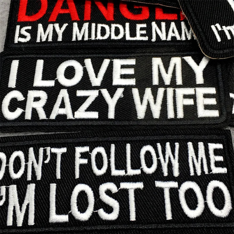 A set of black iron-on text embroidery patches featuring phrases like I love my crazy wife and don't follow me I'm lost too.
