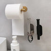 A stainless steel self-adhesive toilet paper holder mounted on a gray wall, next to a white foam refill bottle.