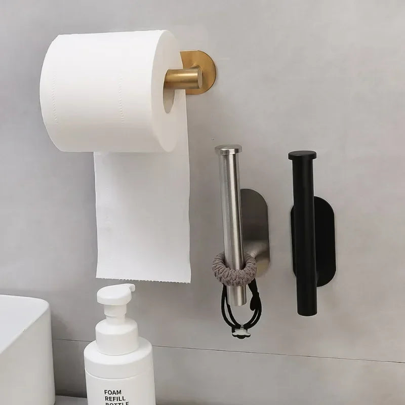 A stainless steel self-adhesive toilet paper holder mounted on a gray wall, next to a white foam refill bottle.