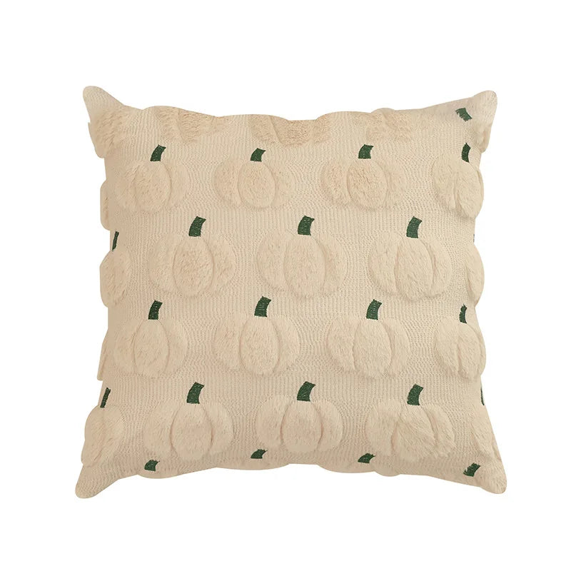 A beige plush throw pillow cover patterned with small green pumpkin shapes.