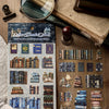A collection of die-cut stickers and vintage-style paper elements for journaling and scrapbooking displayed on a wooden surfa