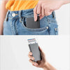 A hand is inserting a slim metal RFID blocking card holder into the pocket of a denim jean.