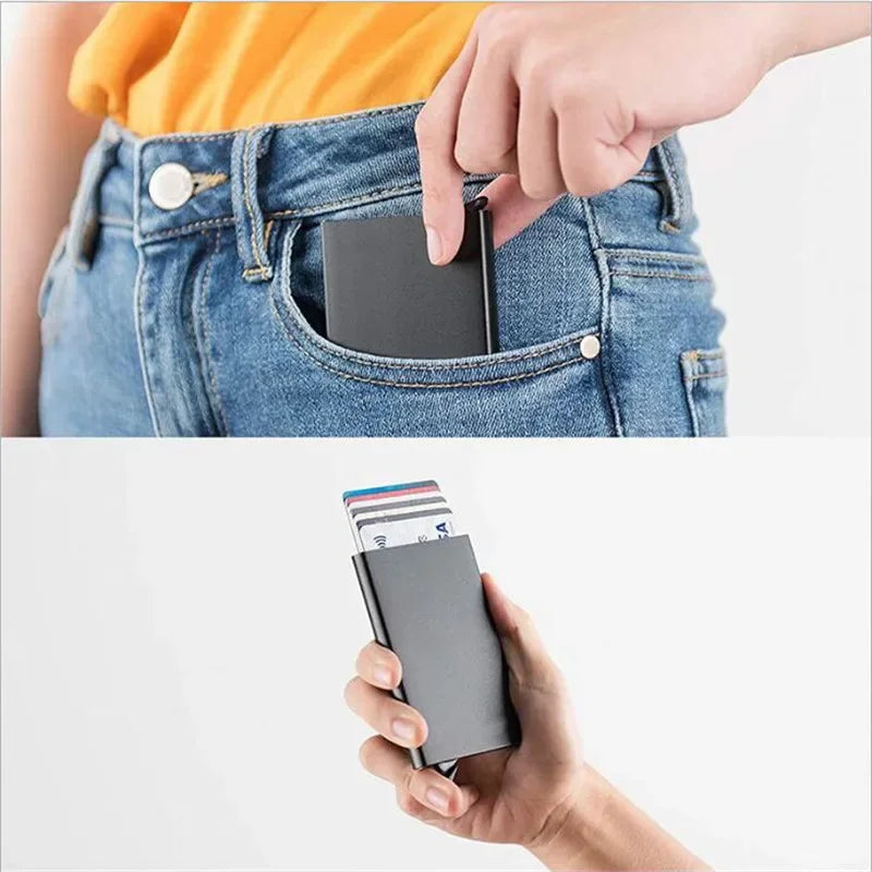 A hand is inserting a slim metal RFID blocking card holder into the pocket of a denim jean.