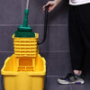 A hand is holding a green mop handle with a yellow basket and a green mop head replacement.